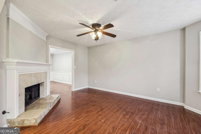 unfurnished living room with dark wood-type flooring, ceiling fan, a tiled fireplace, and a textured ceiling