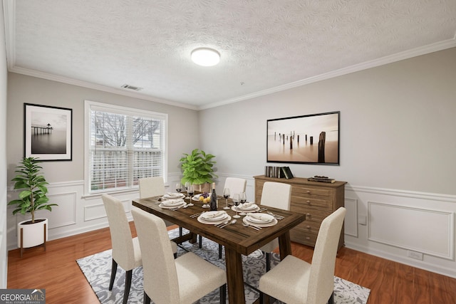 dining area featuring wood-type flooring, crown molding, and a textured ceiling