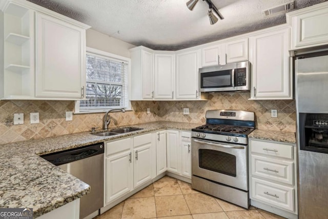 kitchen featuring sink, light tile patterned floors, appliances with stainless steel finishes, light stone countertops, and white cabinets