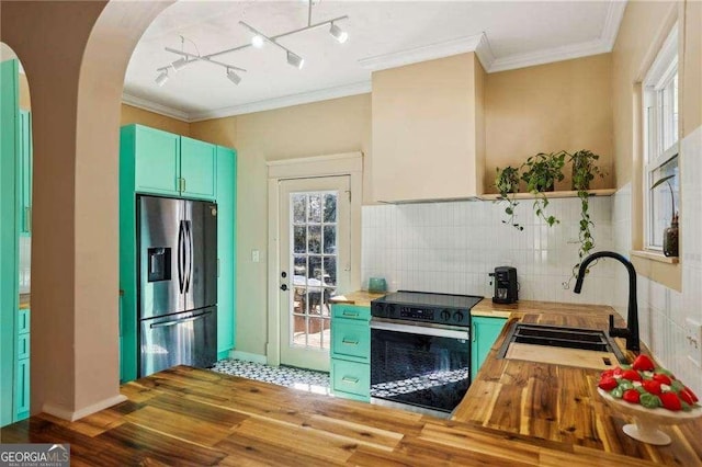 kitchen with sink, crown molding, stainless steel refrigerator with ice dispenser, wood counters, and black / electric stove