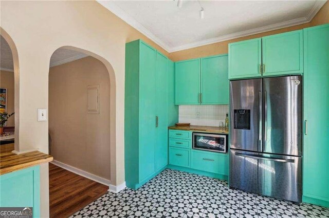 kitchen featuring tasteful backsplash, ornamental molding, green cabinetry, and stainless steel refrigerator with ice dispenser