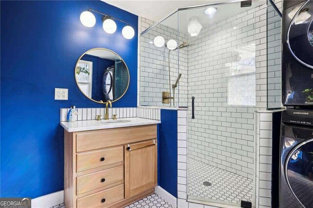 bathroom featuring vanity, washer / dryer, and a shower with shower door