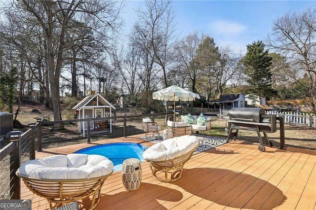 wooden deck with a fenced in pool, an outdoor structure, and an outdoor hangout area