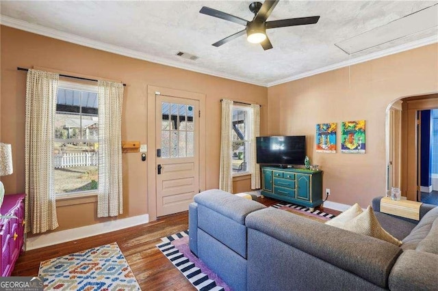 living room with ornamental molding, wood-type flooring, and a healthy amount of sunlight