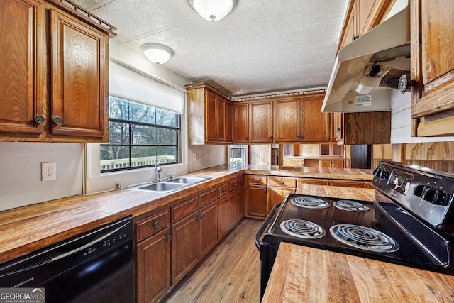 kitchen with sink, light hardwood / wood-style flooring, wood counters, and black appliances