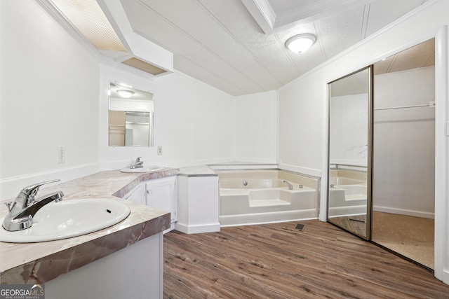 bathroom featuring crown molding, a textured ceiling, vanity, a tub, and hardwood / wood-style floors