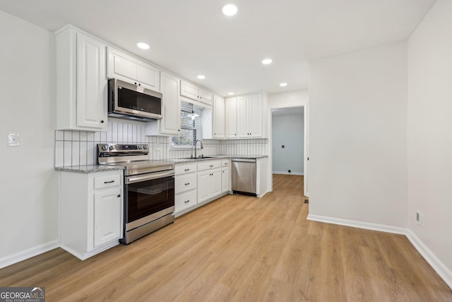 kitchen with sink, white cabinetry, stainless steel appliances, light hardwood / wood-style floors, and decorative backsplash