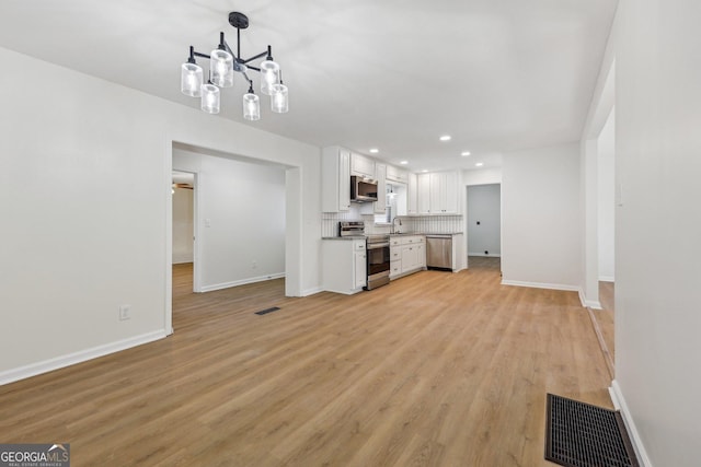 kitchen with stainless steel appliances, sink, white cabinets, and light hardwood / wood-style flooring