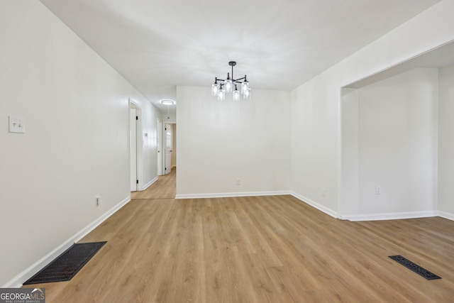 unfurnished dining area with a notable chandelier and light wood-type flooring