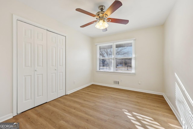 unfurnished bedroom featuring ceiling fan, a closet, and light hardwood / wood-style flooring