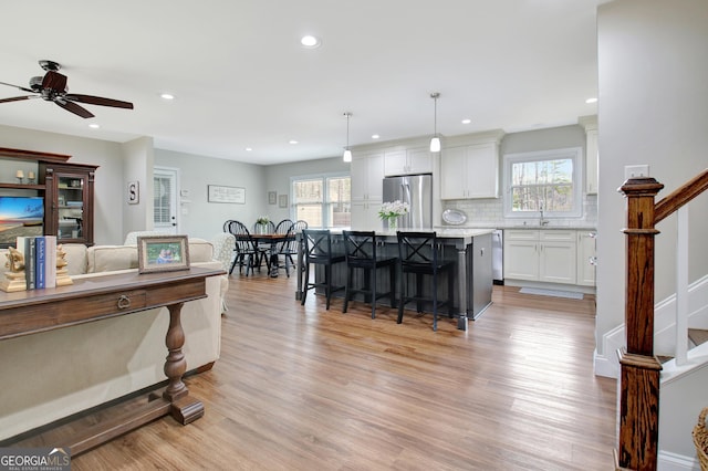 living room featuring plenty of natural light, sink, ceiling fan, and light hardwood / wood-style flooring