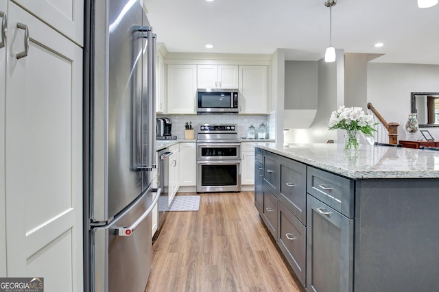 kitchen with pendant lighting, gray cabinetry, white cabinets, backsplash, and stainless steel appliances