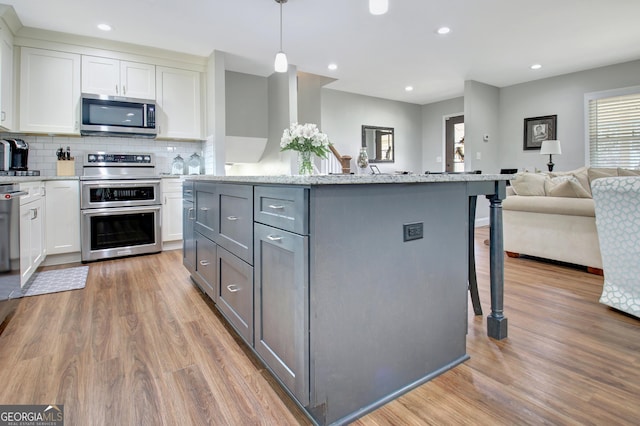 kitchen featuring gray cabinets, white cabinetry, appliances with stainless steel finishes, and pendant lighting