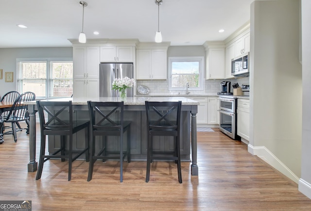 kitchen featuring pendant lighting, light stone countertops, stainless steel appliances, and a kitchen island