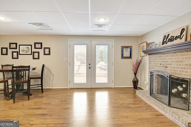 interior space featuring light hardwood / wood-style flooring, a fireplace, french doors, and a paneled ceiling