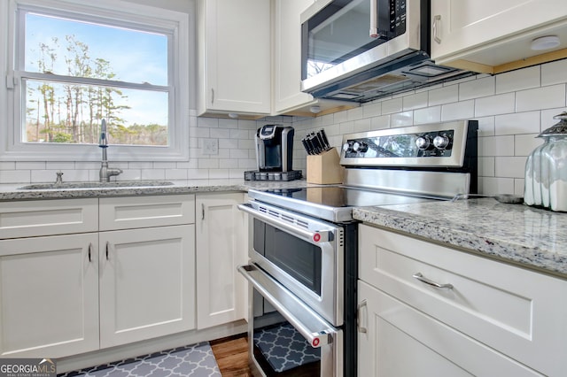 kitchen featuring tasteful backsplash, stainless steel appliances, sink, and white cabinets