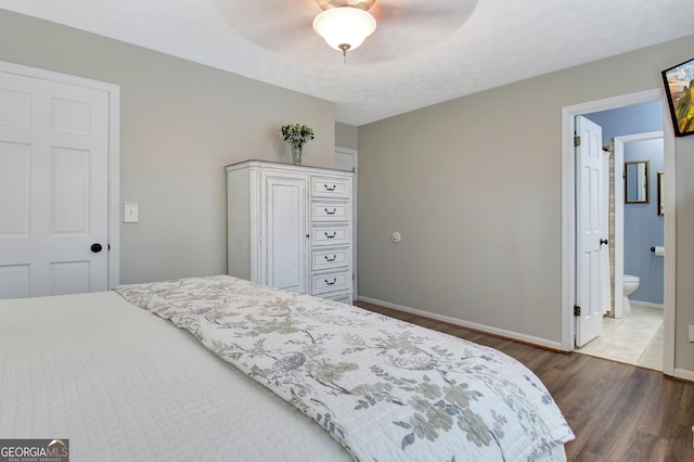 bedroom featuring ensuite bathroom, dark wood-type flooring, a textured ceiling, and ceiling fan