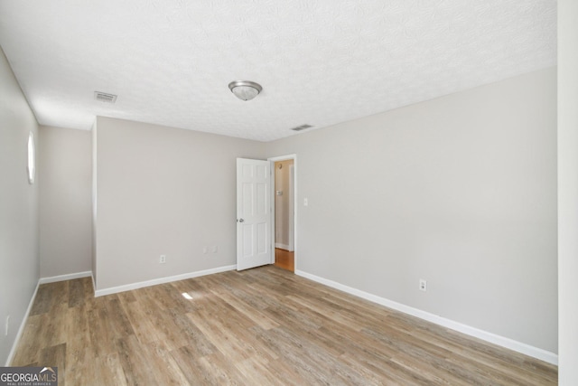 spare room with a textured ceiling and light wood-type flooring