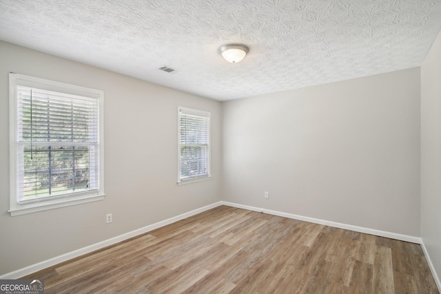 unfurnished room featuring light hardwood / wood-style flooring and a textured ceiling