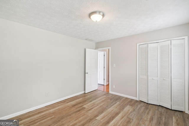 unfurnished bedroom featuring light hardwood / wood-style floors, a closet, and a textured ceiling