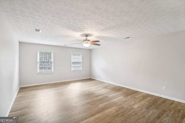 empty room featuring a textured ceiling, light hardwood / wood-style floors, and ceiling fan