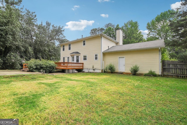 rear view of house featuring a wooden deck and a yard