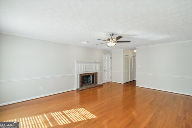 unfurnished living room with hardwood / wood-style floors, a fireplace, a textured ceiling, and ceiling fan