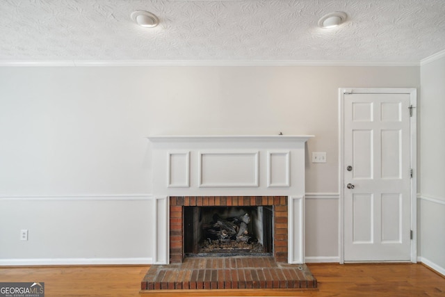 interior details featuring hardwood / wood-style flooring, ornamental molding, a fireplace, and a textured ceiling