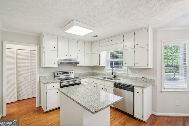 kitchen featuring sink, a kitchen island, stainless steel appliances, light stone countertops, and white cabinets