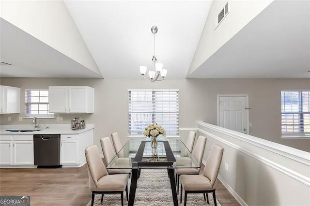 dining area featuring vaulted ceiling, sink, a wealth of natural light, and light hardwood / wood-style floors