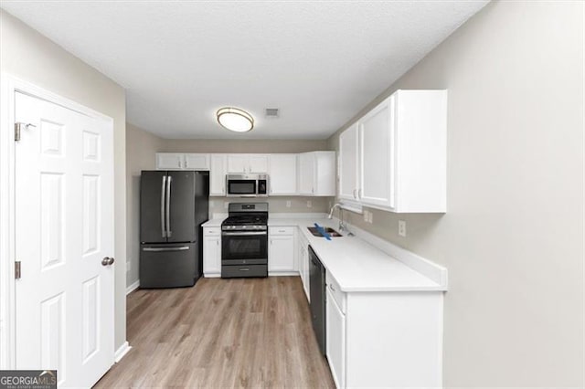 kitchen featuring sink, light hardwood / wood-style floors, white cabinets, and appliances with stainless steel finishes