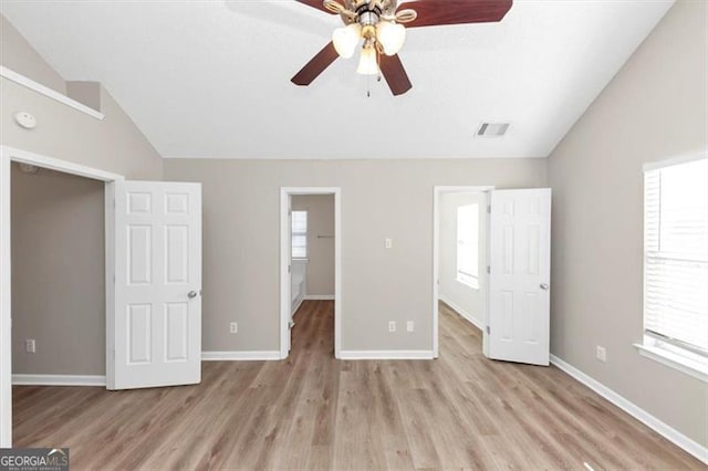 unfurnished bedroom featuring ceiling fan, a spacious closet, vaulted ceiling, and light hardwood / wood-style flooring