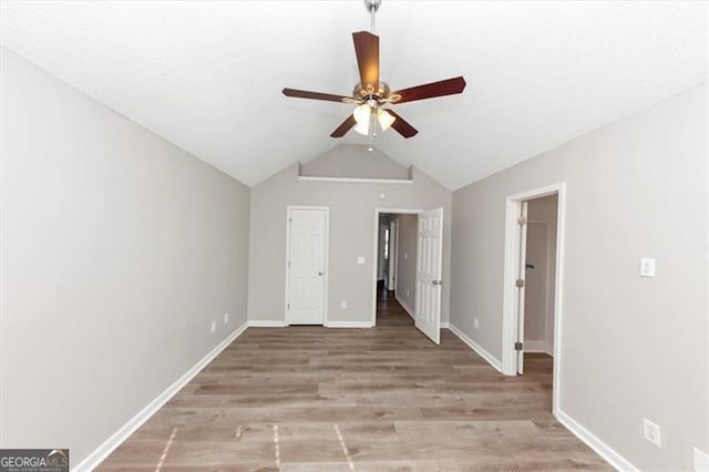 unfurnished bedroom with ceiling fan, lofted ceiling, and light wood-type flooring