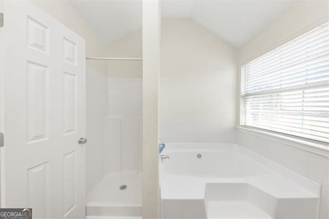 bathroom featuring independent shower and bath and vaulted ceiling