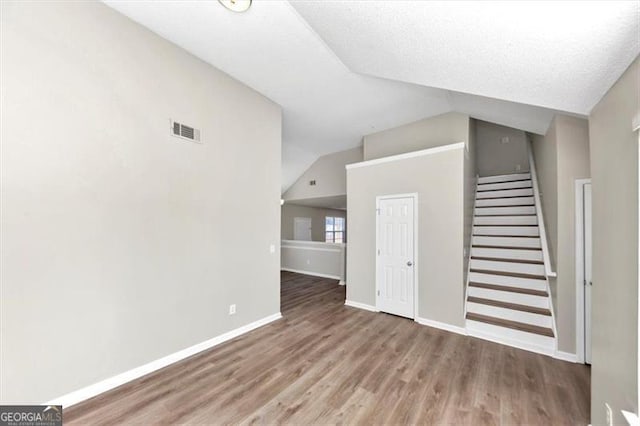 interior space featuring hardwood / wood-style flooring, lofted ceiling, and a textured ceiling