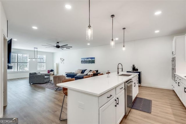 kitchen with dishwasher, sink, a center island with sink, and white cabinets