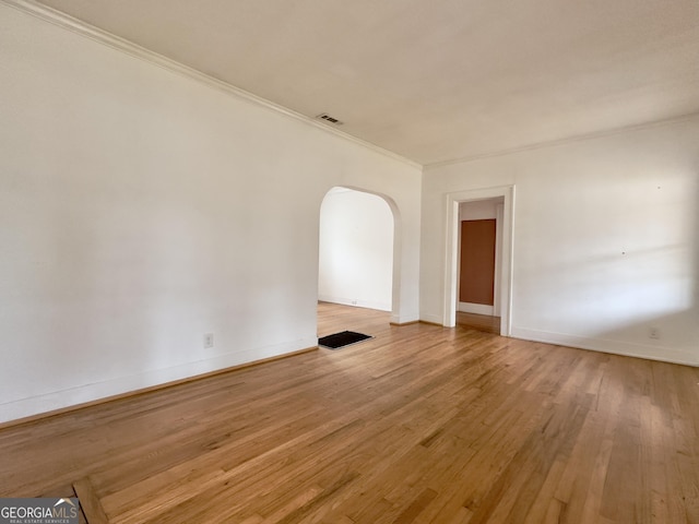 empty room featuring ornamental molding and light wood-type flooring