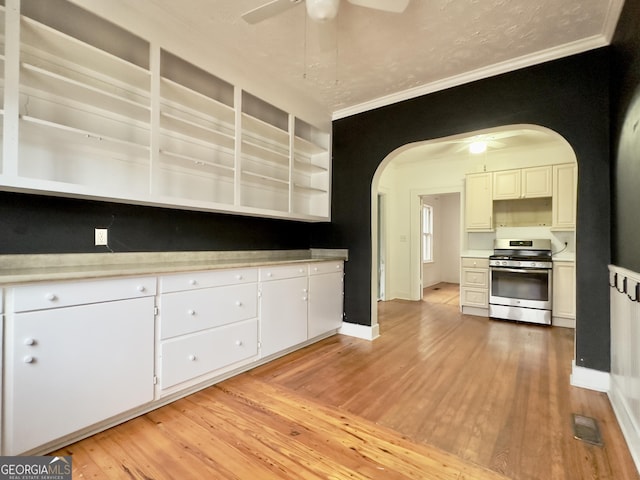 kitchen featuring gas range, ceiling fan, and white cabinets