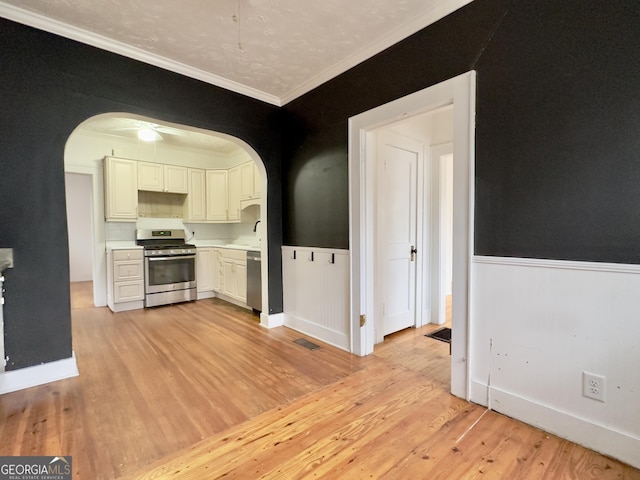 kitchen with sink, white cabinetry, ornamental molding, stainless steel appliances, and light hardwood / wood-style floors