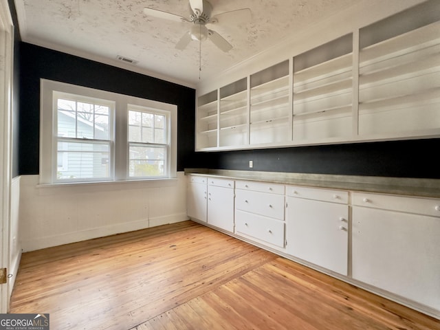 kitchen featuring ceiling fan, a textured ceiling, light hardwood / wood-style flooring, and white cabinets