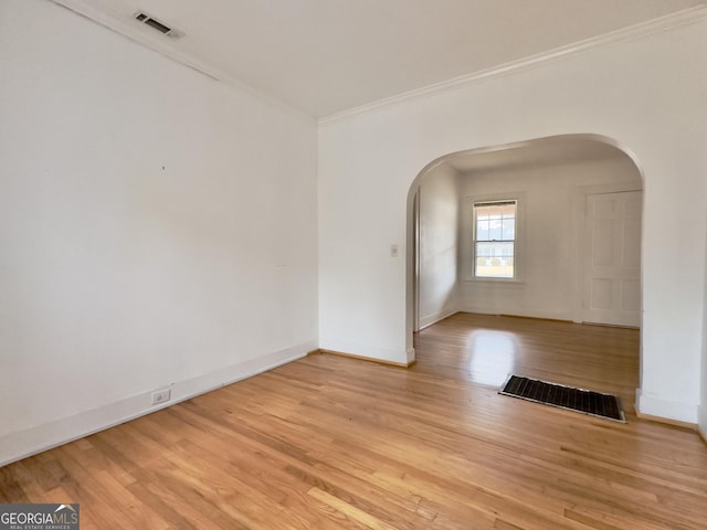 empty room with ornamental molding and light wood-type flooring