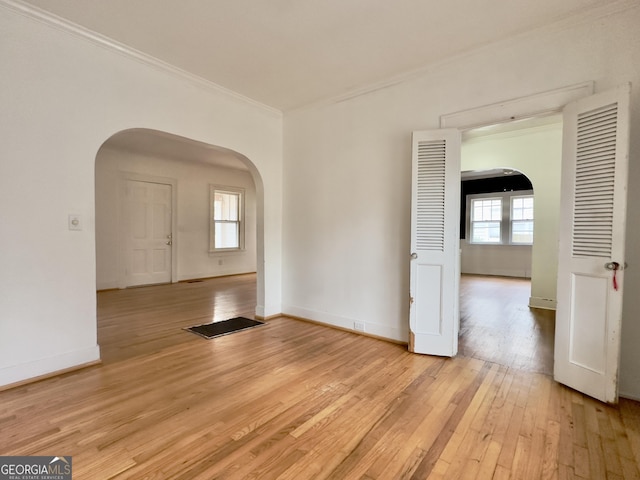 empty room with ornamental molding and light hardwood / wood-style floors