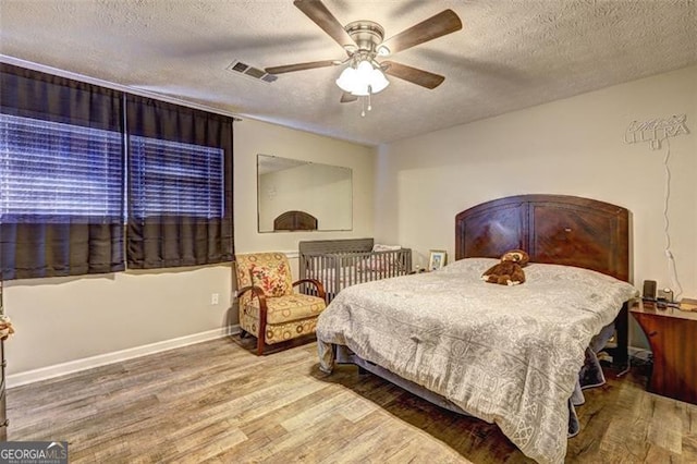 bedroom with hardwood / wood-style floors, a textured ceiling, and ceiling fan