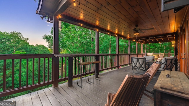 deck at dusk featuring ceiling fan