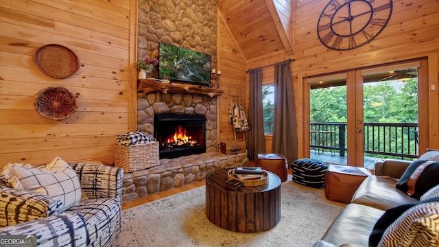 living room with hardwood / wood-style flooring, a stone fireplace, high vaulted ceiling, and wood walls