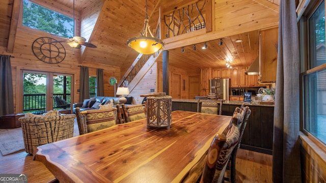 dining space with wooden walls, light wood-type flooring, rail lighting, and wooden ceiling