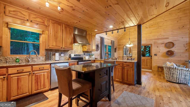 kitchen with decorative light fixtures, a center island, appliances with stainless steel finishes, a kitchen breakfast bar, and wall chimney range hood