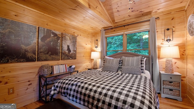 bedroom featuring wood ceiling, wooden walls, light hardwood / wood-style floors, and vaulted ceiling