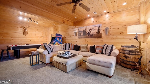 living room featuring wooden walls, rail lighting, carpet, ceiling fan, and wooden ceiling