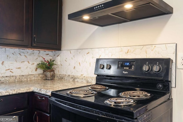 kitchen with dark brown cabinetry, tasteful backsplash, light stone counters, ventilation hood, and black electric range